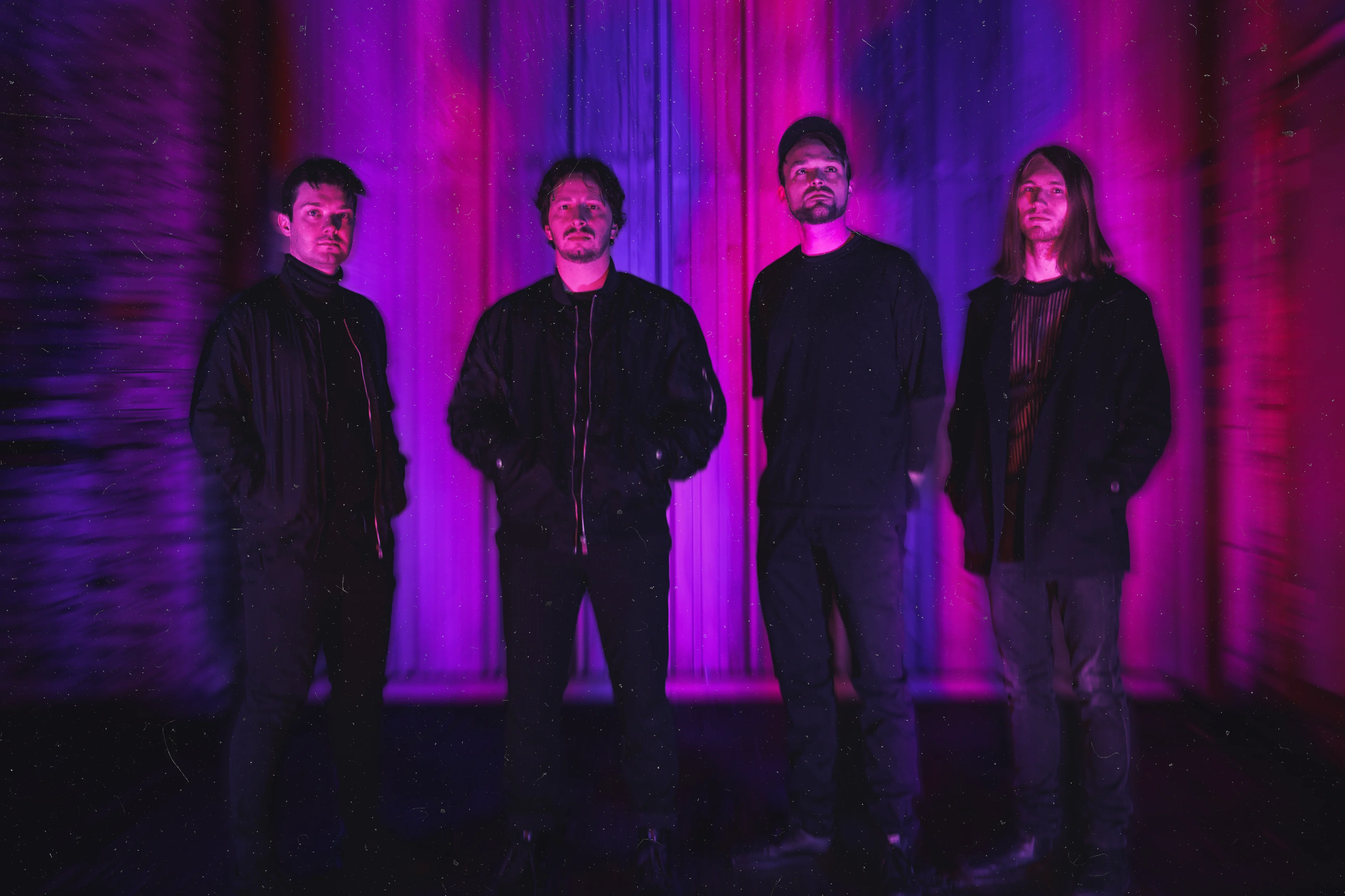 Generation.F: die vier Bandmitglieder vor einer lila und pink beleuchteten Wand